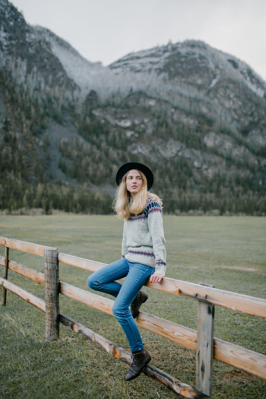 young woman sitting on fence in countryside
